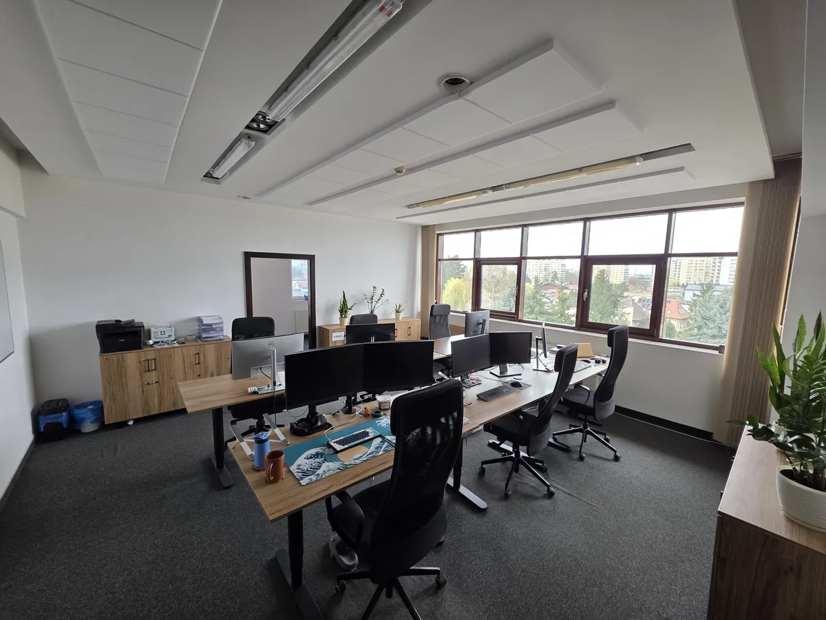 Stanowiska pracy w Mini Office z monitorami, klawiaturami i ergonomicznymi krzesłami